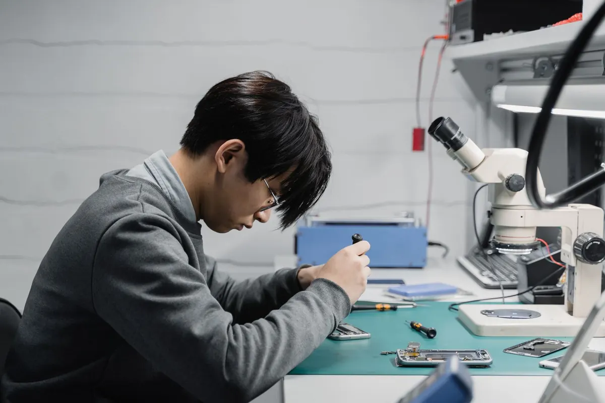 Técnico reparando bajo microscopio